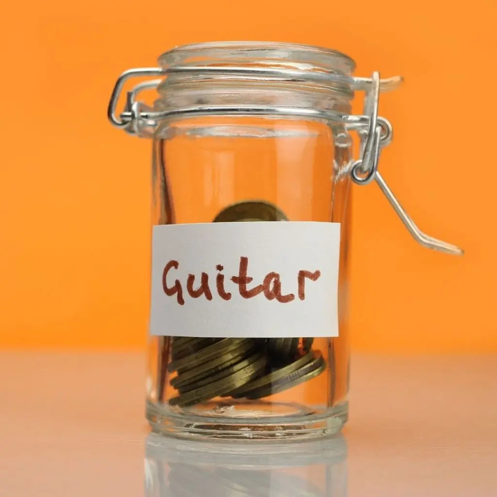Jar with coins and a sticker with the word "guitar" on it
