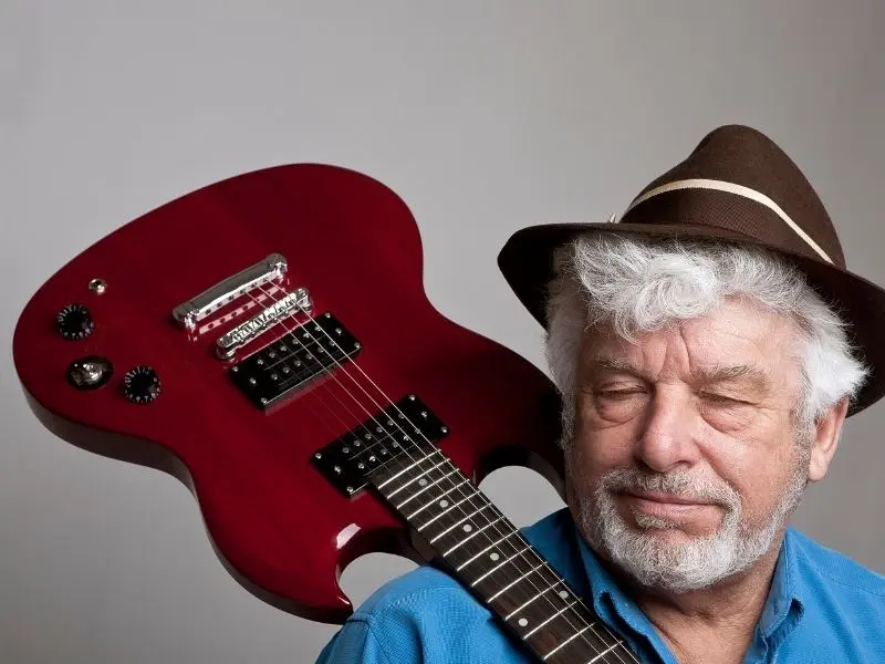 Mature man holding an electric guitar on his shoulder