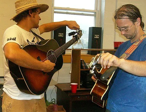 Two men tuning their guitars.