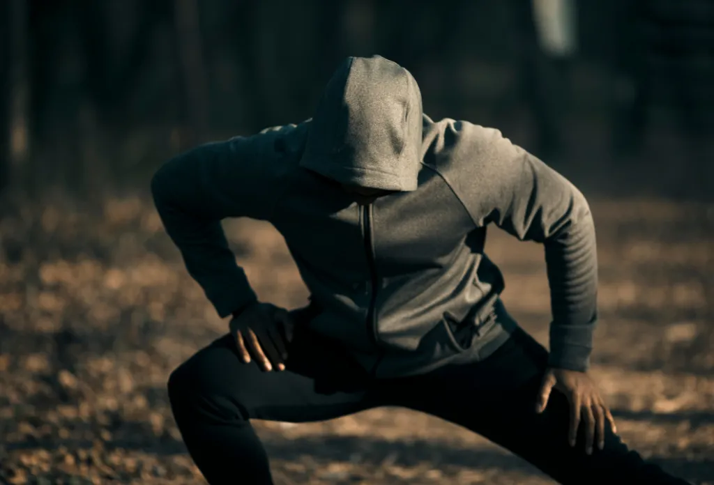 Man in grey sweatsuit stretching