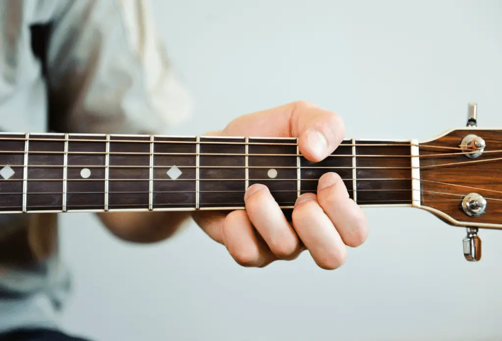 A man shaping a D chord on his acoustic guitar