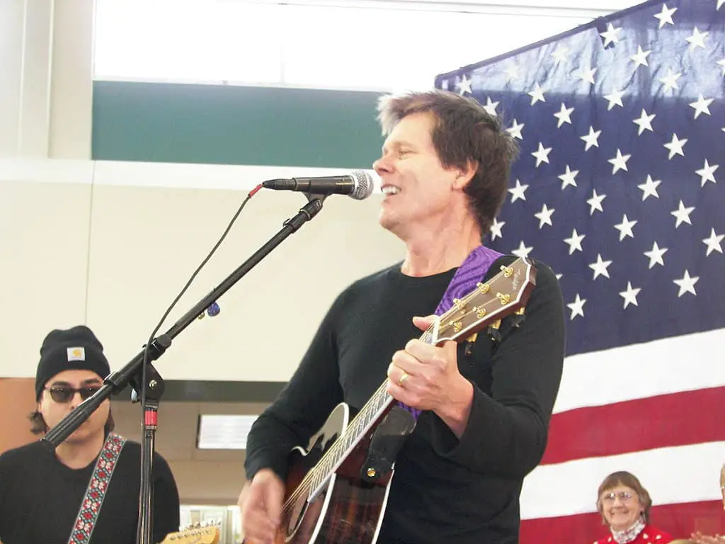 Kevin Bacon playing guitar and singing