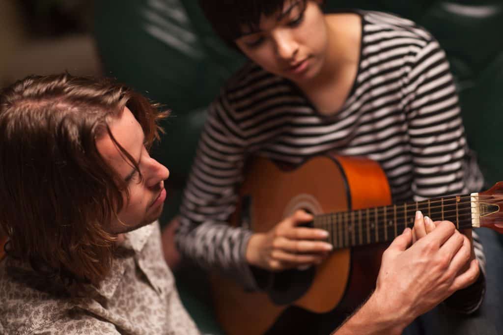 A teacher placing a student's hand on the fretboard.