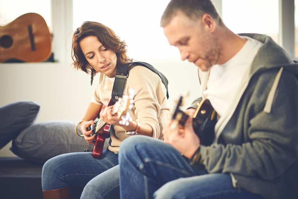 Man and woman playing guitar together.